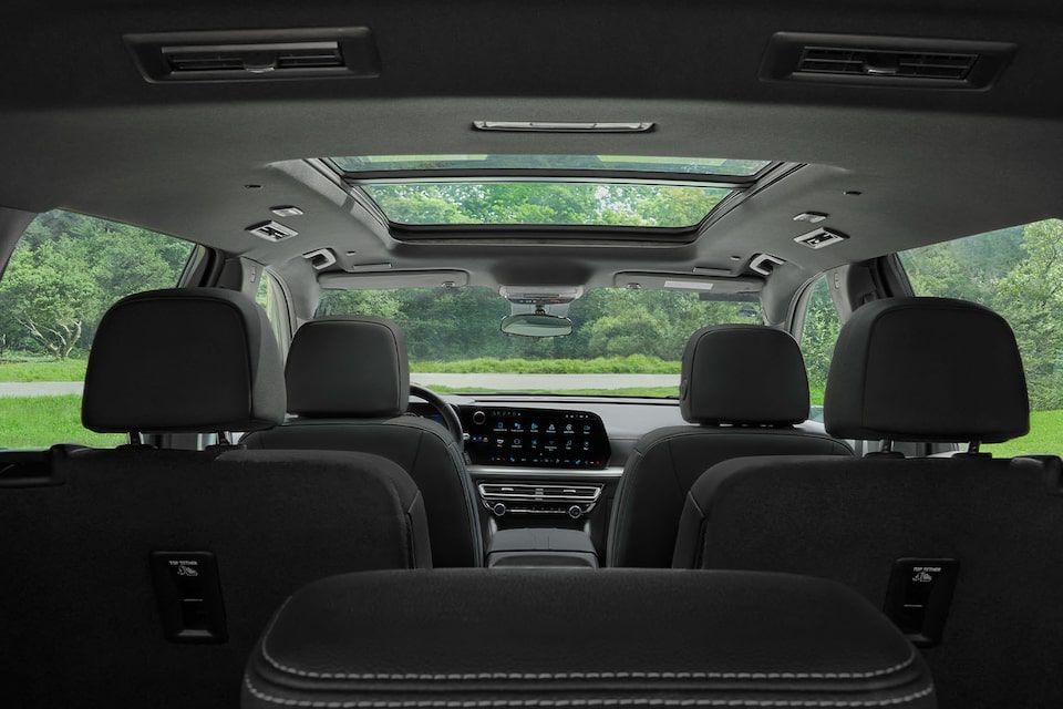 Vista del interior de la Chevrolet Traverse 2025 con techo panorámico, asientos de 3 filas y pantalla digital central