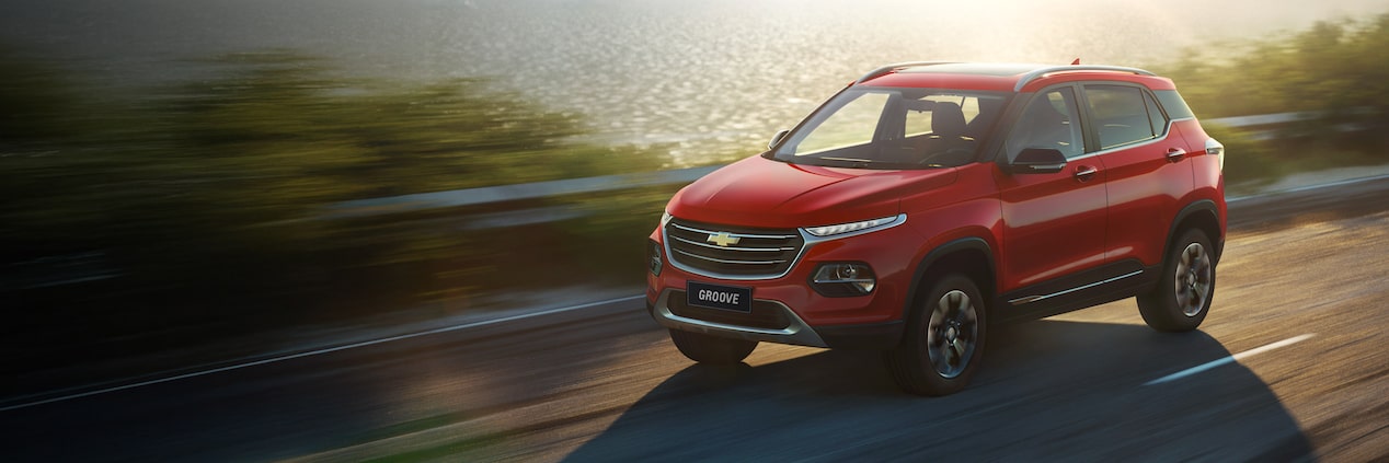 Chevrolet Groove roja en camino al lado de un cuerpo de agua