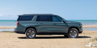 Vista lateral de la Chevrolet Suburban 2025 estacionada frente al mar, destacando diseño elegante y presencia robusta