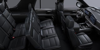 Vista completa del interior de la Chevrolet Suburban con tres filas de asientos en cuero negro y tablero digital