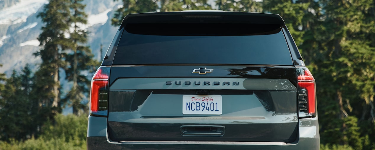 Vista trasera de Chevrolet Suburban SUV con paisaje montañoso de fondo