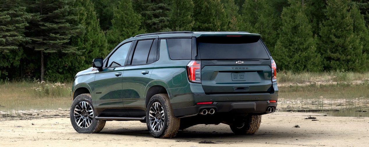 Vista trasera de la Chevrolet Tahoe 2025 Z71 en color verde, en terreno off-road junto a un bosque