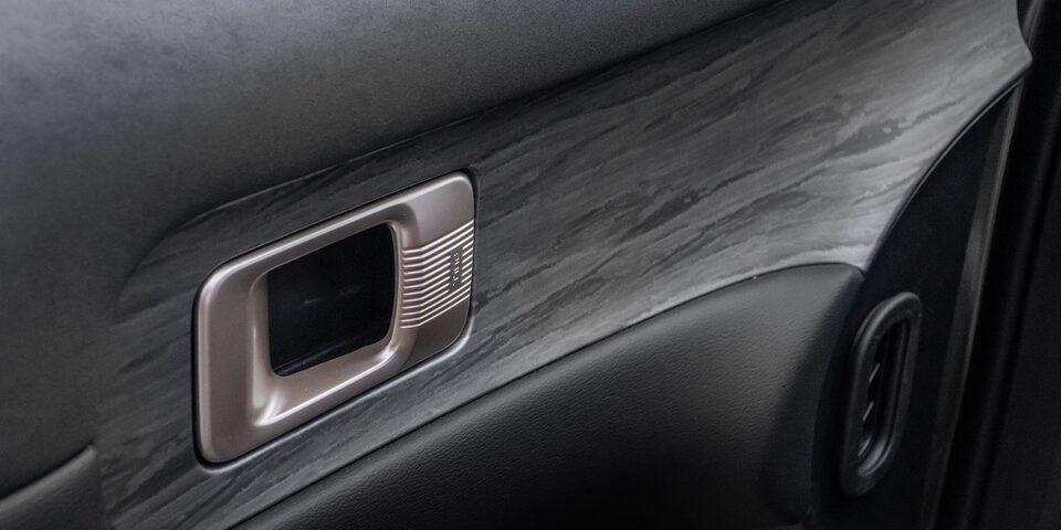 Vista en detalle de del panel interior de la Chevrolet Captiva EV con acabado simil madera y manija metálica.