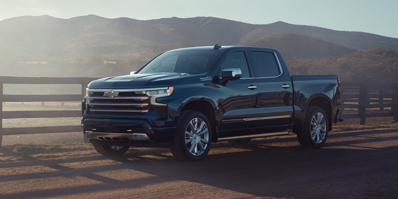 Chevrolet Silverado High Country estacionada al lado del camino con montañas de fondo.