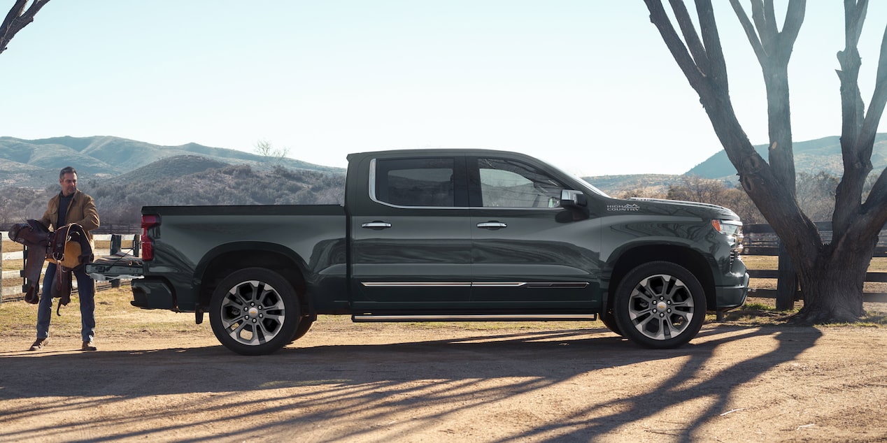 Vista lateral de la Chevrolet High Country con un hombre cargando la caja.