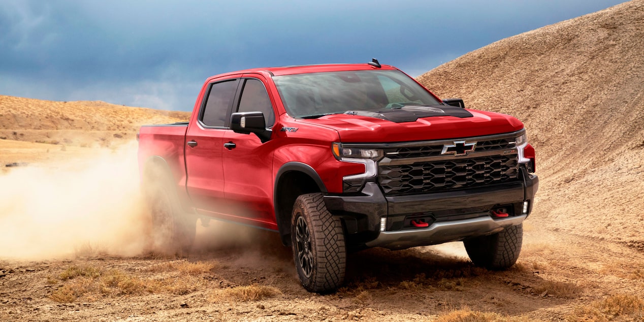 Chevrolet Silverado ZR2 circulando en un camino de tierra con montañas de fondo.