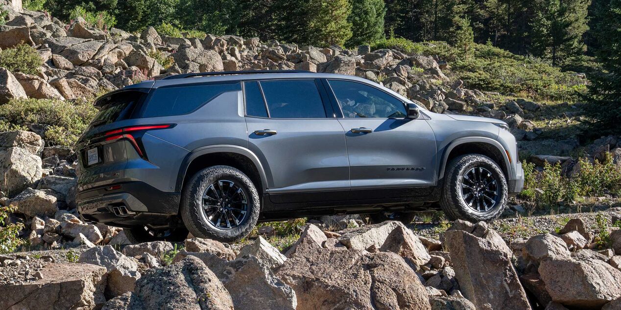Vista lateral de Chevrolet Traverse cruzando un camino de piedras.