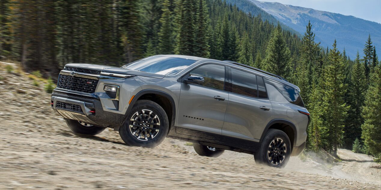 Vista lateral Chevrolet Traverse andando en camino de piedra.